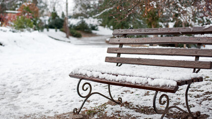 Bench in the winter park. rest in the city park. autumn season, nature, outdoor hiking. wooden bench in the snow closeup, resting place. cold winter season. first snow. the wooden bench is covered ice