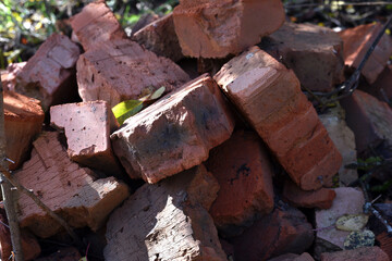 Fototapeta premium old brick. red brick. a haphazardly thrown pile of old broken bricks. a concept of a ruin, a war or natural disaster, construction, renovation. for background and text. close-up