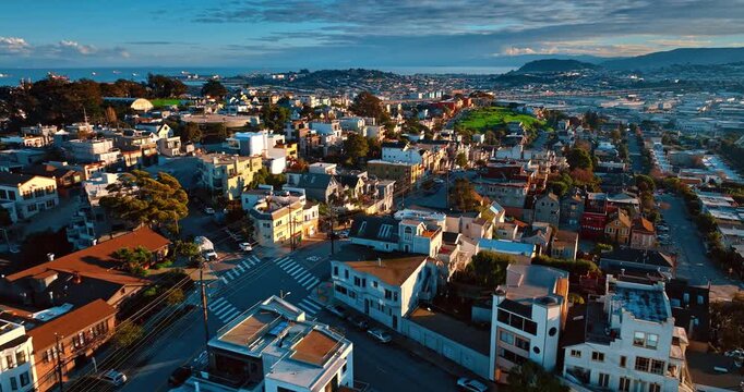 Setting sun lights the houses. Footage over the residential neighborhoods of San Francisco, California, USA with sloping streets. Aerial view.