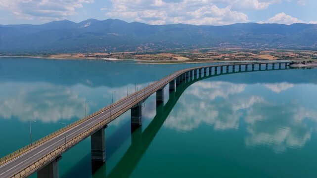 Aerial view of Lake Polyfytos in Greece with a curved bridge,