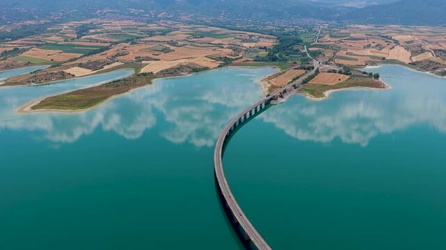 Aerial view of Lake Polyfytos in Greece with a curved bridge,