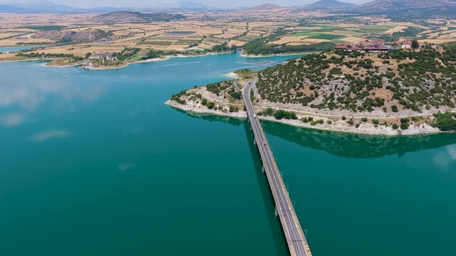 Aerial view of Lake Polyfytos in Greece with a curved bridge,