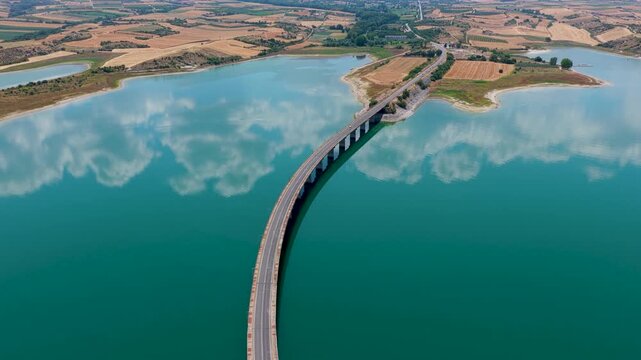 Aerial view of Lake Polyfytos in Greece with a curved bridge,