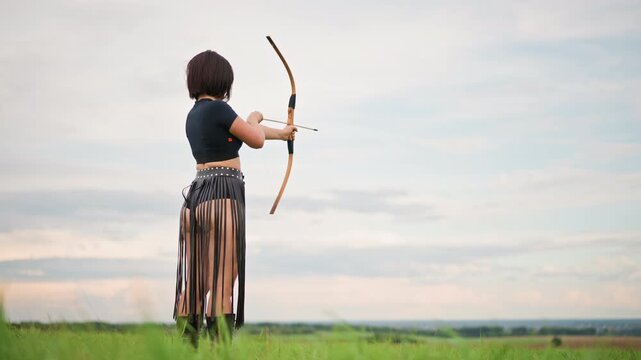 lone archer in grassy field aiming, leather skirt and quiver visible as figure draws traditional bow toward distant horizon under soft clouded sky, conveying solitude, focus, and warrior resilience