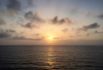 Obraz premium Sunset Over the Ocean with Cloudy Sky