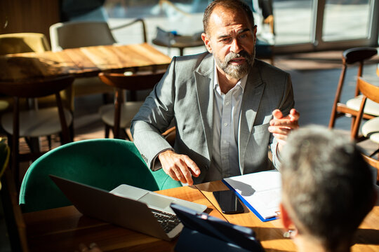 Mature business meeting client in cafe with laptop