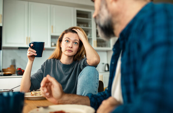 Concerned woman talking with partner at kitchen table