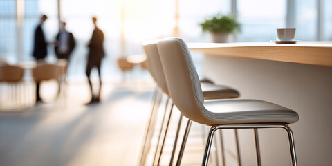 Modern interior with focus on bar stools and blurred business people conversing in background during daylight