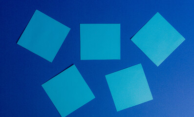 Five turquoise square sticky notes arranged on a dark blue background, space for text and office concepts.