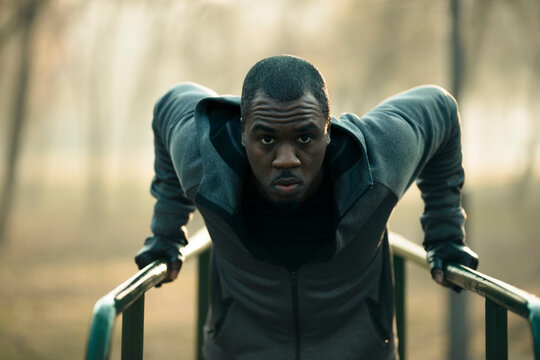 Male athlete performing triceps dips on outdoor parallel bars