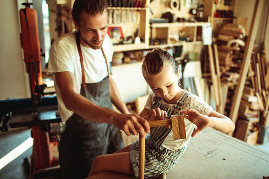 Father teaching daughter woodworking in home workshop