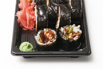 Salmon sushi takeaway tray. Lunch box with salmon rolls. Fresh Japanese food set. Black plastic container on white background. Ready meal for lunch. Studio top view.