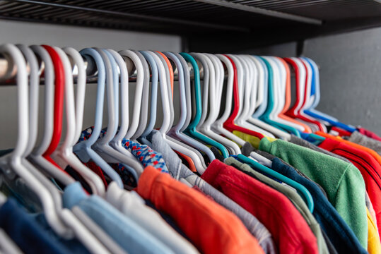 Colorful Casual Kids Shirts Neatly Arranged on Plastic Hangers in Organized Closet