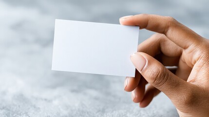 Obraz premium A hand holds a blank business card against a textured background, emphasizing simplicity and potential for personalization.