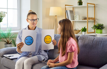 Therapy session with psychologist and child discussing emotions. Counselor uses emotion cards to help the girl name feelings and build communication. Mental health and emotional support concept. © Studio Romantic