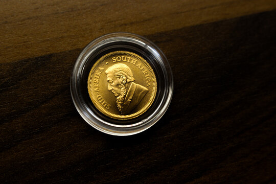 close up of a shiny krugerrand gold coin laying on a wooden underground