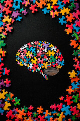 autism awareness concept featuring a colorful puzzle brain surrounded by puzzle pieces on a dark background