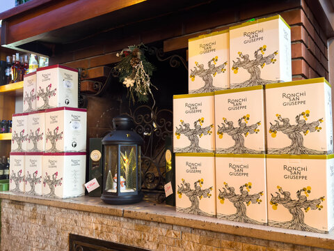 Tarvisio, Italy - January 15, 2026: Boxes of Ronchi San Giuseppe wine stacked on a stone shelf beside a decorative lantern and bar area with bottles in the background