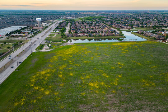 Aerial view of suburban landscape with open field lake residential houses and connecting roads