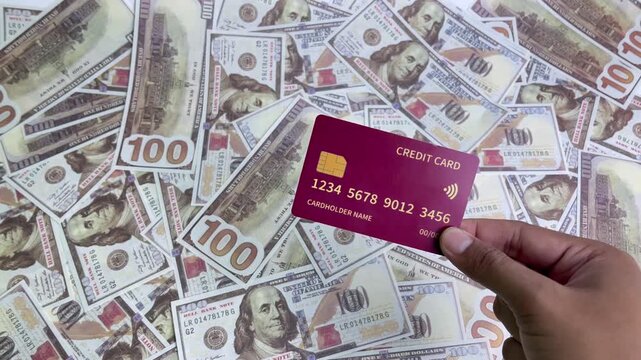 A close-up view of a hand holding a credit card and a dollar bill. An illustration of finance and business using dollars.