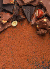 Chocolate pieces with cocoa powder background and copy space