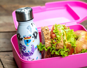 A vibrant pink bento lunch box featuring a fresh salad sandwich, red apple, and a reusable water bottle. Perfect for healthy diet ads, school nutrition, and sustainable living concepts.