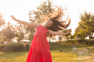 beautiful teenage brunette girl with long hair, smiling, looking at the camera during a summer walk