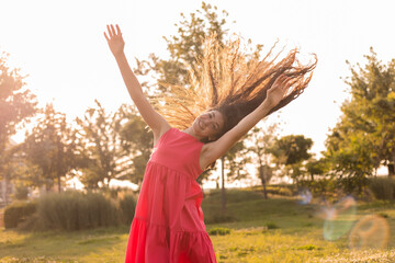 beautiful teenage brunette girl with long hair, smiling, looking at the camera during a summer walk