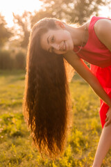 beautiful teenage brunette girl with long hair, smiling, looking at the camera during a summer walk
