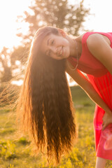 beautiful teenage brunette girl with long hair, smiling, looking at the camera during a summer walk