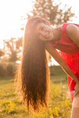 beautiful teenage brunette girl with long hair, smiling, looking at the camera during a summer walk