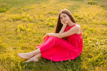 beautiful teenage brunette girl with long hair, smiling, looking at the camera during a summer walk