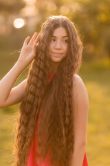 beautiful teenage brunette girl with long hair, smiling, looking at the camera during a summer walk