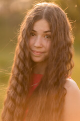 beautiful teenage brunette girl with long hair, smiling, looking at the camera during a summer walk