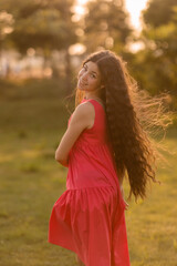beautiful teenage brunette girl with long hair, smiling, looking at the camera during a summer walk