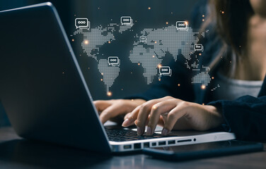 Business professional typing on laptop with global chat icons, representing online communication, worldwide collaboration, digital messaging, remote work, and international business connectivity.