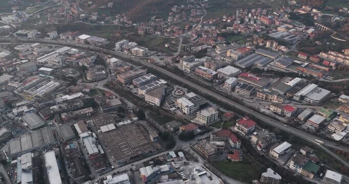 Aerial view of tanning factory buildings with solar panels along a highway, blending urban architecture with the natural landscape, Solofra, Campania, Italy.