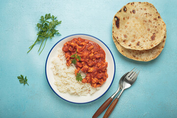 Indian chicken curry with basmati rice served on plate with chapati flatbread on the side top view