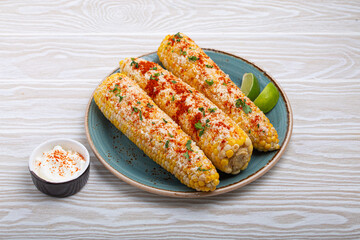 Delicious Mexican dish Elotes corn cob covered in spices and cheese