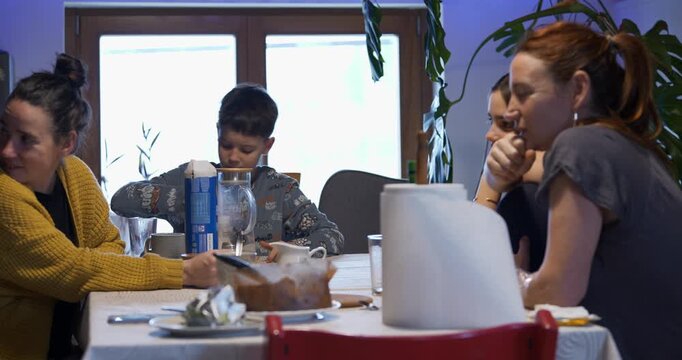 During breakfast, a boy excitedly gestures while accusing a family member of being the imposter in the mobile app game.