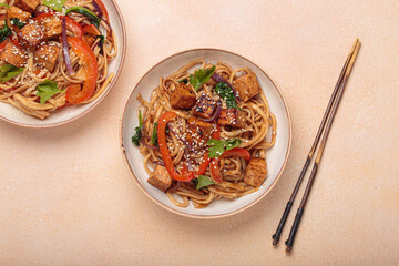 Udon noodles with fried tofu and vegetables garnished with sesame seeds
