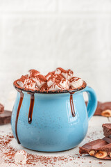 Cup of hot chocolate with marshmallows and chocolate drizzle on light background. copy space