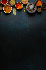 Mortar and pestle surrounded by colorful spices on dark background with copy space
