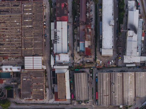 Aerial view of industrial tanning factory buildings cast long shadows in the fading light, highlighting the geometric patterns of rooftops and roads, Solofra, Campania, Italy.
