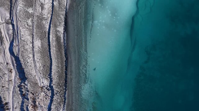 An impressive drone shot showing the turquoise waters of Lake Salda and its white magnesium mineral shores from a vertical perspective.