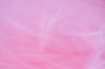 Abstract soft pink background with blurred tulle fabric texture. Minimalist romantic backdrop for Valentine's Day, beauty, or feminine design