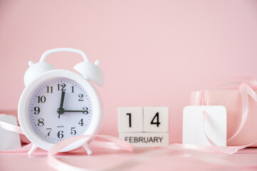 White alarm clock with pink gift boxes and blank gift tags on pink background. Time for celebration, Valentine's Day concept