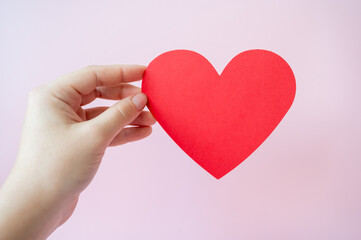 Red heart on pink background in hand. Valentine's Day celebration concept