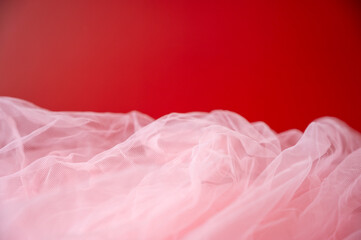 Red background with soft white tulle fabric border. Festive romantic backdrop for Valentine's Day or wedding