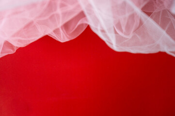 Red background with soft white tulle fabric border. Festive romantic backdrop for Valentine's Day or wedding